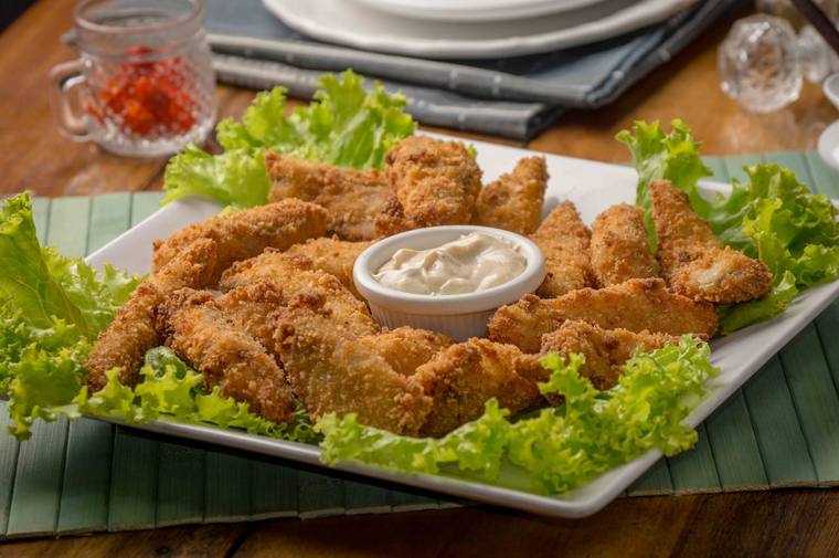 Krokante kipreepjes op een bord met sla en een bakje dipsaus